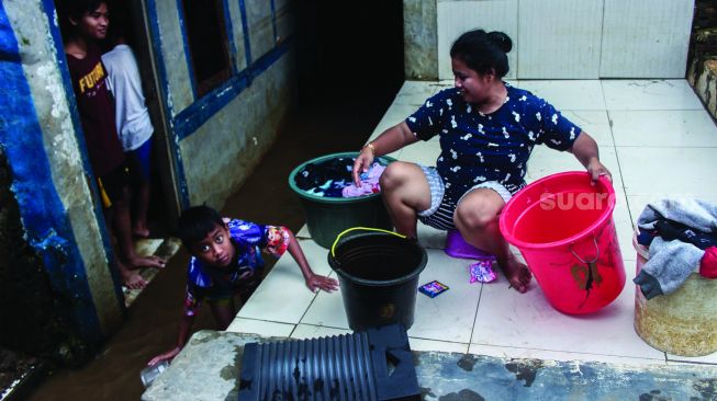 Warga permukiman kebon pala berkativitas saat banjir di Kampung Melayu, Jatinegara, Jakarta Timur, Kamis (17/2/2022). [Suara.com/Septian]