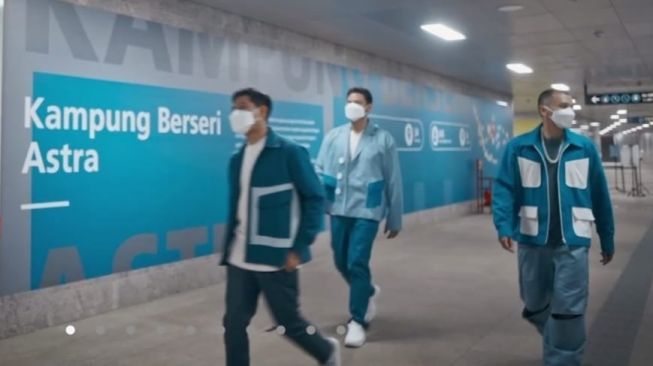 Cuplikan videoclip lagu tema atau theme song HUT 65 tahun Astra "Selalu Bersama" yang menunjukkan tiga personel RAN turun dari MRT menuju Kampung Berseri Astra [bidik layar presscon/suara.com/CNR ukirsari].