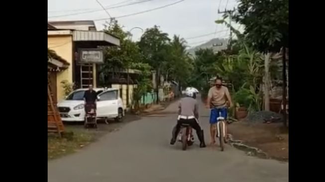 Seorang polisi menunggangi motor nyeleneh dan stop pesepeda di jalan (Facebook)