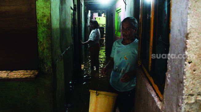 Warga permukiman kebon pala berkativitas saat banjir di Kampung Melayu, Jatinegara, Jakarta Timur, Kamis (17/2/2022). [Suara.com/Septian]