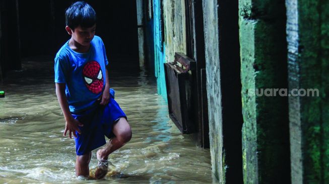 Warga permukiman kebon pala berkativitas saat banjir di Kampung Melayu, Jatinegara, Jakarta Timur, Kamis (17/2/2022). [Suara.com/Septian]