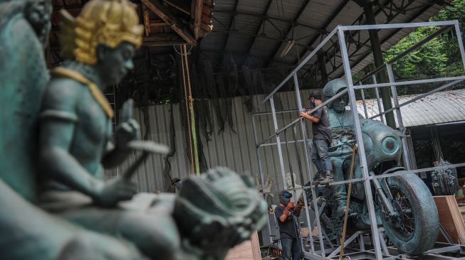 Pekerja memasang rangka untuk mengemas patung Presiden Joko Widodo yang menaiki sepeda motor di NuArt Sculpture Park, Bandung, Jawa Barat, Jumat (18/2/2022). ANTARA FOTO/Raisan Al Farisi