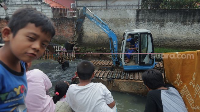 Petugas mengoperasikan alat berat saat melakukan pengerukan di Kali Mampang, Pondok Jaya, Jakarta, Sabtu (19/2/2022). [Suara.com/Angga Budhiyanto]