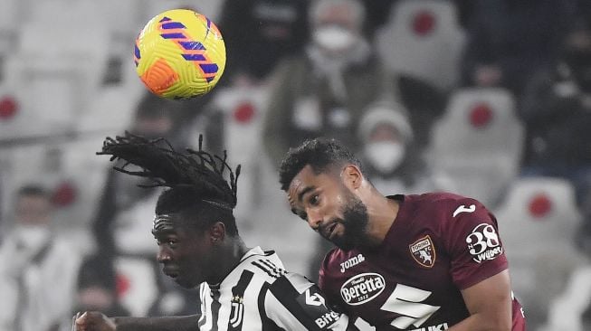 Penyerang Juventus Moise Kean (kiri) berebut bola dengan bek Koffi Djidji selama pertandingan sepak bola Serie A Italia Juventus melawan Torino di stadion Allianz, Turin, Italia, Sabtu (19/2/2022) dini hari WIB. Filippo MONTEFORTE / AFP