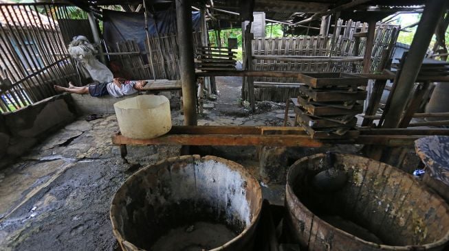 Pembuat tahu beristirahat di tempat kerjanya ketika melakukan mogok produksi di pabrik tahu di Indramayu, Jawa Barat, Sabtu (19/2/2022). ANTARA FOTO/Dedhez Anggara