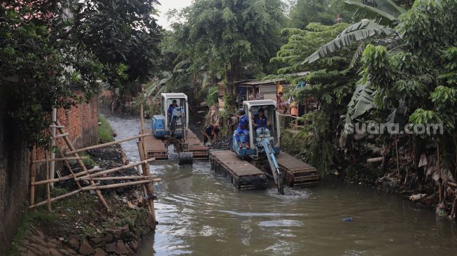 Petugas mengoperasikan alat berat saat melakukan pengerukan di Kali Mampang, Pondok Jaya, Jakarta, Sabtu (19/2/2022). [Suara.com/Angga Budhiyanto]