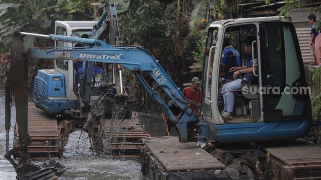 Petugas mengoperasikan alat berat saat melakukan pengerukan di Kali Mampang, Pondok Jaya, Jakarta, Sabtu (19/2/2022). [Suara.com/Angga Budhiyanto]