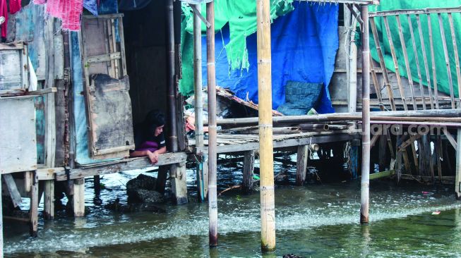 Aktivitas warga sekitar saat banjir Rob di pelabuhan Muara Angke, Jakarta Utara, Minggu (20/2/2022).  [Suara.com/Septian]