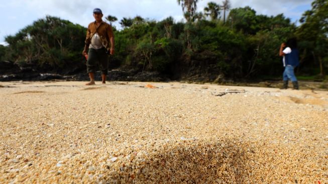 Pengunjung berjalan di pasir pantai Parang Ireng Taman Nasional Alas Purwo, Banyuwangi, Jawa Timur, Sabtu (19/2/2022).[ANTARA FOTO/Budi Candra Setya/aww]