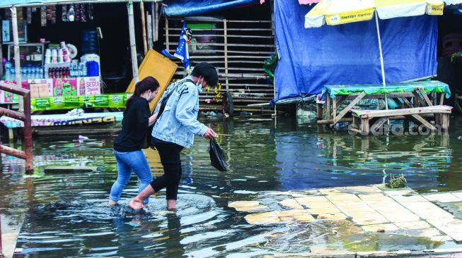 Aktivitas warga sekitar saat banjir Rob di pelabuhan Muara Angke, Jakarta Utara, Minggu (20/2/2022).  [Suara.com/Septian]