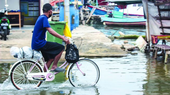 Aktivitas warga sekitar saat banjir Rob di pelabuhan Muara Angke, Jakarta Utara, Minggu (20/2/2022).  [Suara.com/Septian]