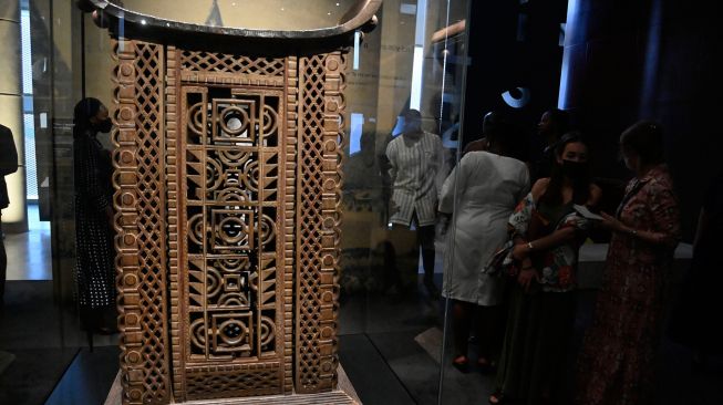 Pengunjung melihat tahta Kerajaan Raja Glele dari Kerajaan Dahomey saat pameran artefak Benin yang dijarah dan pameran karya seni kontemporer yang digelar di kantor kepresidenan di Cotonou, Benin, Jumat (18/2/2022). [PIUS UTOMI EKPEI/AFP] 