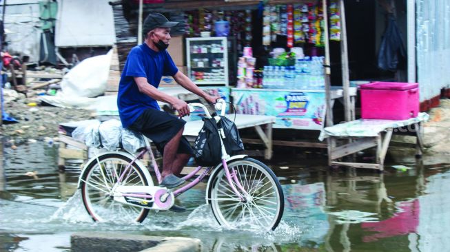 Aktivitas warga sekitar saat banjir Rob di pelabuhan Muara Angke, Jakarta Utara, Minggu (20/2/2022).  [Suara.com/Septian]