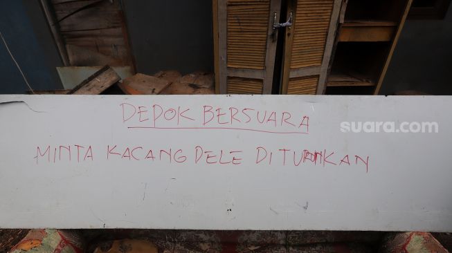 Papan bertuliskan protes kenaikan harga kedelai berada di kawasan Sentra Produksi Tempe, Cimanggis, Depok, Jawa Barat, Senin (21/2/2022). [Suara.com/Angga Budhiyanto]