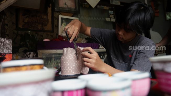 Andika Dwi Pangga (16) menyelesaikan pembuatan batik rekat pada media pot bunga di Say Galery, Sukmajaya, Depok, Jawa Barat, Senin (21/2/2021). [Suara.com/Angga Budhiyanto]