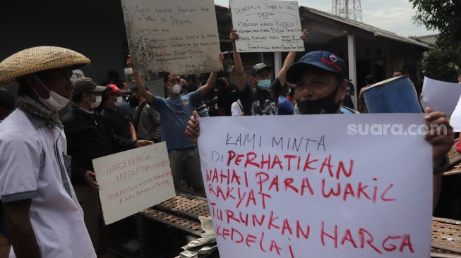 Sejumlah perajin tempe melakukan aksi unjuk rasa di kawasan Sentra Produksi Tempe, Cimanggis, Depok, Jawa Barat, Senin (21/2/2022). [Suara.com/Angga Budhiyanto]