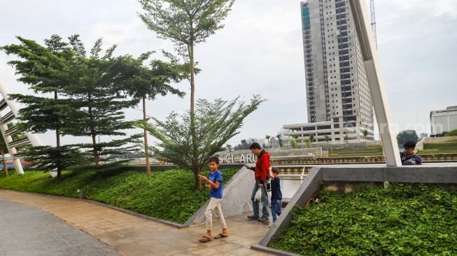 Warga saat berkunjung ke taman Tarum Bhagasasi, Kalimalang, Bekasi, Jawa Barat, Senin (21/2/2022). [Suara.com/Alfian Winanto]