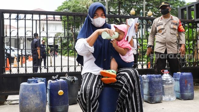 Warga Muara Angke melakukan aksi sambil membawa jeriken kosong di depan Gedung Balai Kota DKI Jakarta, Jakarta Pusat, Selasa (22/2/2022). [Suara.com/Alfian Winanto]