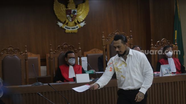 Terdakwa yang juga musisi I Gede Ari Astina atau Jerinx Superman is Dead (SID) menjalani sidang lanjutan kasus pengancaman melalui media elektronik pada Adam Deni beragendakan pleidoi atau pembacaan nota pembelaan di Pengadilan Negeri (PN) Jakarta Pusat, Jakarta, Selasa (22/2/2022). [Suara.com/Angga Budhiyanto]