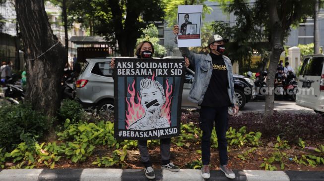 Penggemar musisi Jerinx SID dan band Superman Is Dead (SID), Outsider menggelar aksi solidaritas di depan Pengadilan Negeri (PN) Jakarta Pusat, Jakarta, Selasa (22/2/2022). [Suara.com/Angga Budhiyanto]