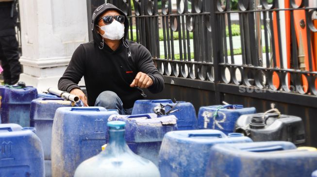 Warga Muara Angke melakukan aksi sambil membawa jeriken kosong di depan Gedung Balai Kota DKI Jakarta, Jakarta Pusat, Selasa (22/2/2022). [Suara.com/Alfian Winanto]