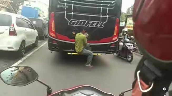 Pria bergelantungan di belakang bus. (Instagram/@terangmedia)