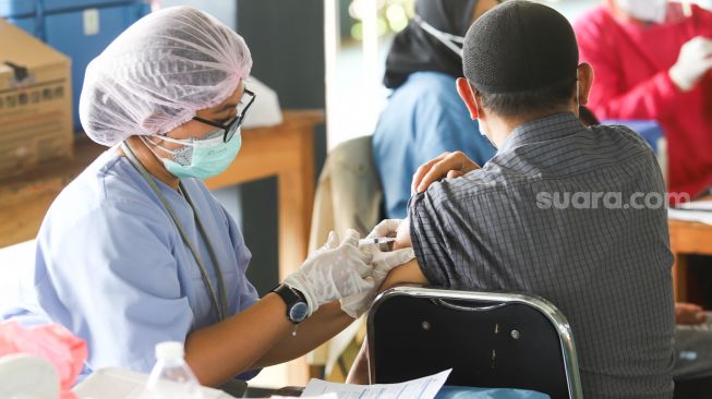 Petugas kesehatan menyuntikan vaksin Covid-19 kepada warga di Pondok Pesantren Minhajurrosyidin, Jakarta Timur, Selasa (22/2/2022). Petugas kesehatan menyuntikan vaksin Covid-19 kepada warga di Pondok Pesantren Minhajurrosyidin, Jakarta Timur, Selasa (22/2/2022). [Suara.com/Alfian Winanto]