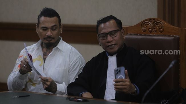 Terdakwa yang juga musisi I Gede Ari Astina atau Jerinx Superman is Dead (SID) bersiap menjalani sidang lanjutan kasus pengancaman melalui media elektronik pada Adam Deni beragendakan pleidoi atau pembacaan nota pembelaan di Pengadilan Negeri (PN) Jakarta Pusat, Jakarta, Selasa (22/2/2022). [Suara.com/Angga Budhiyanto]