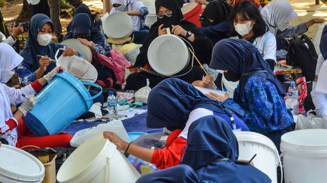 Sejumlah siswa melukis di atas media ember di Alun-alun Kota Tasikmalaya, Jawa Barat, Rabu (23/2/2022). ANTARA FOTO/Adeng Bustomi

