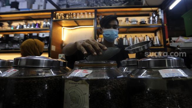 Pramuniaga melayani pembeli biji kopi di Toko Dunia Kopi, Pasar Santa, Jakarta, Rabu (23/2/2022). [Suara.com/Angga Budhiyanto]