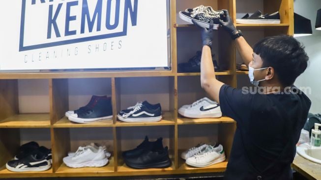 Kru menaruh sepatu pelanggan yang sudah dibersihkan di Cleaning Shoes Kicks Kemon, Haji Nawi, Jakarta Selatan, Rabu (23/2/2022). [Suara.com/Alfian Winanto]