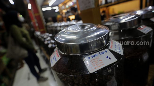 Deretan toples berisi biji kopi dipajang di Toko Dunia Kopi, Pasar Santa, Jakarta, Rabu (23/2/2022). [Suara.com/Angga Budhiyanto]