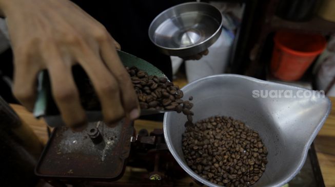 Pramuniaga menimbang biji kopi pesanan pelanggan di Toko Dunia Kopi, Pasar Santa, Jakarta, Rabu (23/2/2022). [Suara.com/Angga Budhiyanto]