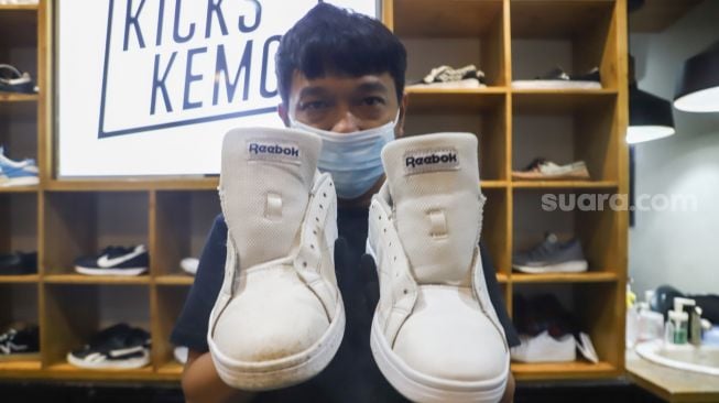 Kru menunjukkan sepatu pelanggan yang sudah dibersihkan di Cleaning Shoes Kicks Kemon, Haji Nawi, Jakarta Selatan, Rabu (23/2/2022). [Suara.com/Alfian Winanto]