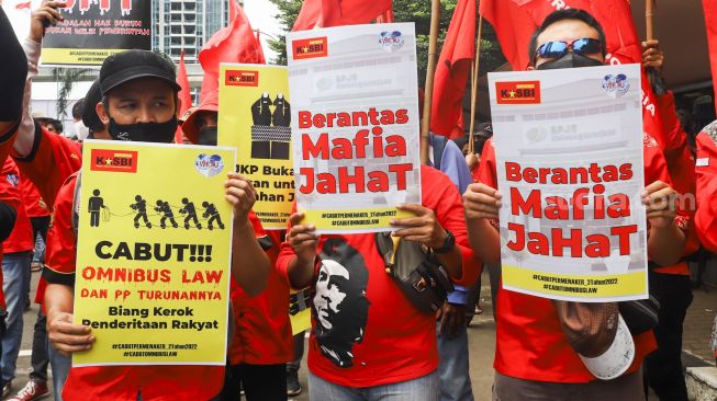 Massa buruh membawa poster dan spanduk berisi tuntutan saat menggelar aksi unjuk rasa di depan gedung Kementerian Tenaga Kerja (Kemenaker) di Setia Budi, Jakarta Selatan, Rabu (23/2/2022). [Suara.com/Alfian Winanto]