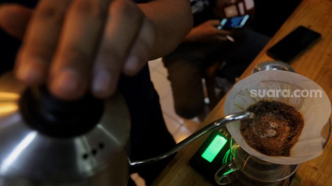 Barista meracik kopi di Toko Dunia Kopi, Pasar Santa, Jakarta, Rabu (23/2/2022). [Suara.com/Angga Budhiyanto]