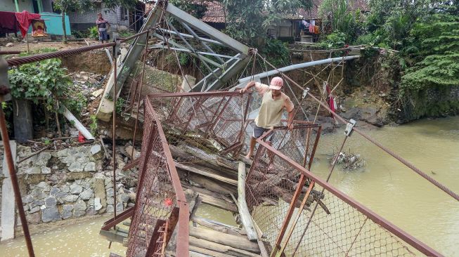 Warga memaksakan diri melintasi jembatan rusak di Desa Sukarasa, Tanjung Sari, Kabupaten Bogor, Jawa Barat, Kamis (24/2/2022). ANTARA FOTO/Yulius Satria Wijaya