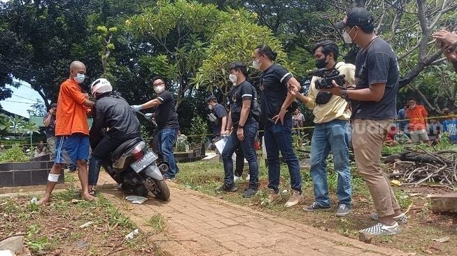 Salah satu tersangka memeragakan adegan dalam rekonstruksi kasus pembunuhan Ficky Firlana di TPU Kober, Ulujami, Jakarta Selatan, Kamis (24/2/2022). [Suara.com/Muhammad Jehan Nurhakim]