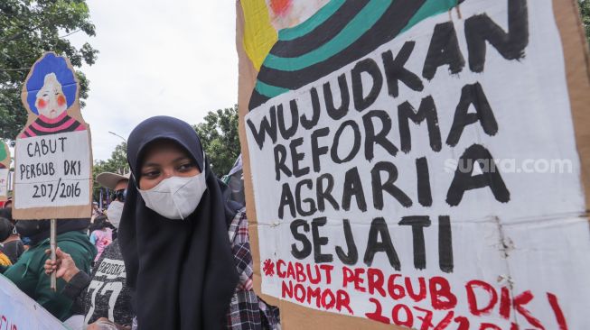 Massa yang tergabung dalam Koalisi Rakyat Menolak Penggusuran (KRMP) menggelar aksi di depan Balai Kota DKI Jakarta, Jakarta Pusat, Kamis (24/2/2022). [Suara.com/Alfian Winanto]