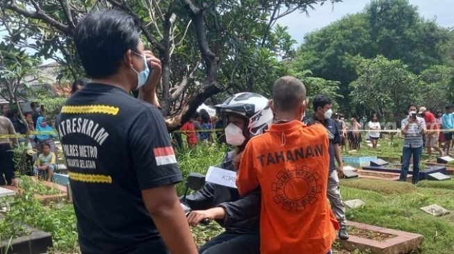 Salah satu tersangka memeragakan adegan dalam rekonstruksi kasus pembunuhan Ficky Firlana di TPU Kober, Ulujami, Jakarta Selatan, Kamis (24/2/2022). [Suara.com/Muhammad Jehan Nurhakim]