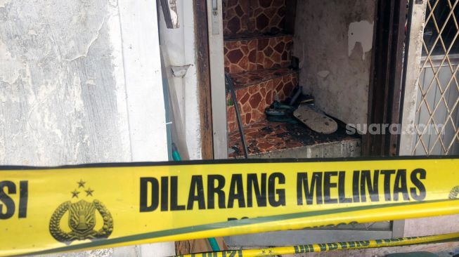 Garis polisi yang melintang di depan pintu kaca, akses utama rumah yang terbakar di Jalan Taman Radio Dalam 7, Kebayoran Lama, Jakarta Selatan, Sabtu (26/2/2022). [Suara.com/Faqih Fathurrahman]