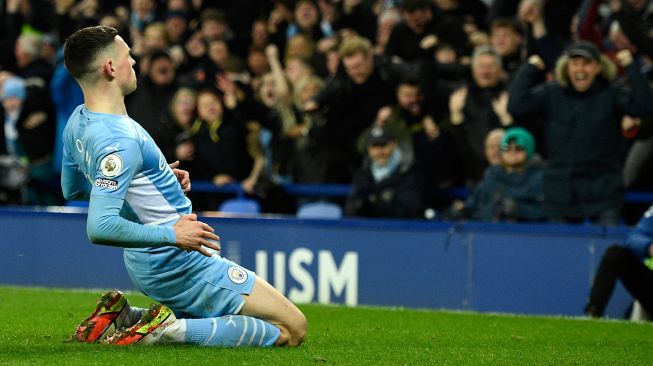 Gelandang Manchester City Phil Foden merayakan gol pertama timnya saat pertandingan sepak bola Liga Premier Inggris antara Everton dan Manchester City di Stadion Goodison Park, Inggris, Sabtu (26/2/2022). [Oli SCARFF / AFP]