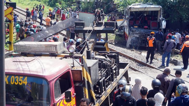 Suasana evakuasi bangkai bus pariwisata PO Harapan Jaya yang tertabrak KA Rapih Doho di perlintasan kereta api tanpa palang pintu di Desa Ketanon, Tulungagung, Jawa Timur, Minggu (27/2/2022). [ANTARA FOTO/Deny Trisdanto//DS/aww]