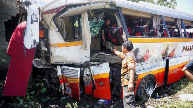 Suasana evakuasi bangkai bus pariwisata PO Harapan Jaya yang tertabrak KA Rapih Doho di perlintasan kereta api tanpa palang pintu di Desa Ketanon, Tulungagung, Jawa Timur, Minggu (27/2/2022). [ANTARA FOTO/Deny Trisdanto//DS/aww]