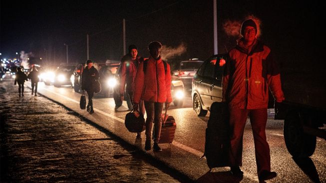 Orang-orang berjalan kaki dan naik mobil untuk menyeberang dari Ukraina ke Polandia di perbatasan Korczowa-Krakovets, Sabtu (26/2/2022). [Dimitar DILKOFF/AFP]