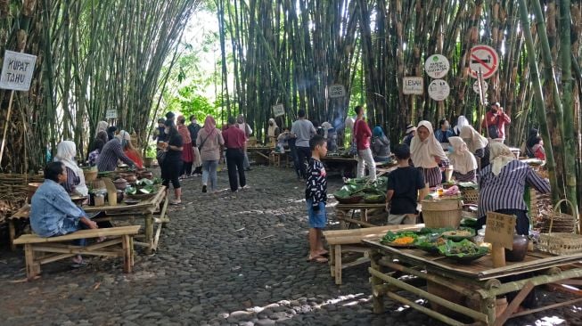 Suasana interaksi pengunjung dengan pedagang di pasar Papringan Ngadiprono, Kedu, Temanggung, Jawa Tengah, Minggu (27/2/2022). [ANTARA FOTO/Anis Efizudin/aww]