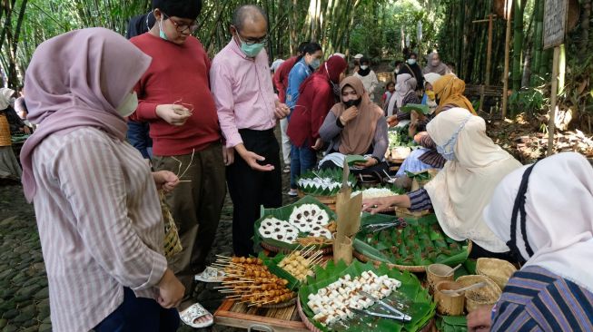 Suasana interaksi pengunjung dengan pedagang di pasar Papringan Ngadiprono, Kedu, Temanggung, Jawa Tengah, Minggu (27/2/2022). [ANTARA FOTO/Anis Efizudin/aww]