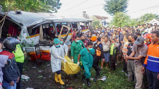 Petugas mengevakuasi jenazah korban kecelakaan bus pariwisata PO Harapan Jaya yang tertabrak KA Rapih Doho di perlintasan kereta api tanpa palang pintu di Desa Ketanon, Tulungagung, Jawa Timur, Minggu (27/2/2022). [ANTARA FOTO/Deny Trisdanto//DS/aww]