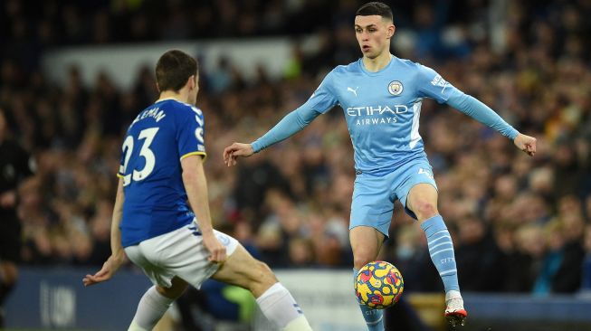 Bek Everton Seamus Coleman (kiri) bersaing dengan gelandang Manchester City Phil Foden (kanan) saat pertandingan sepak bola Liga Premier Inggris antara Everton dan Manchester City di Stadion Goodison Park, Inggris, Sabtu (26/2/2022). [Oli SCARFF / AFP]
