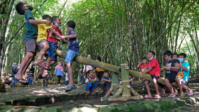 Sejumlah anak bermain jungkat-jungkit bambu di pasar Papringan Ngadiprono, Kedu, Temanggung, Jawa Tengah, Minggu (27/2/2022). [ANTARA FOTO/Anis Efizudin/aww]